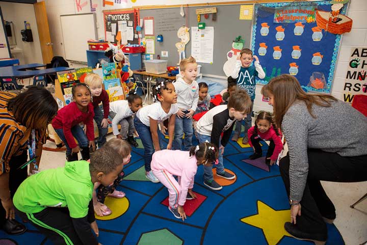 Children in preschool stretching during circle time.