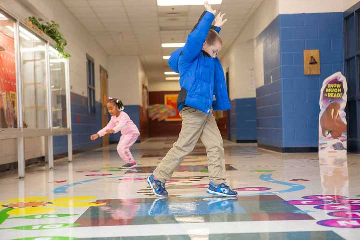 Children jumping on a letter pathway in the hall.