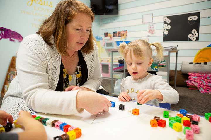 Teacher working with child using blocks and triangle shape.